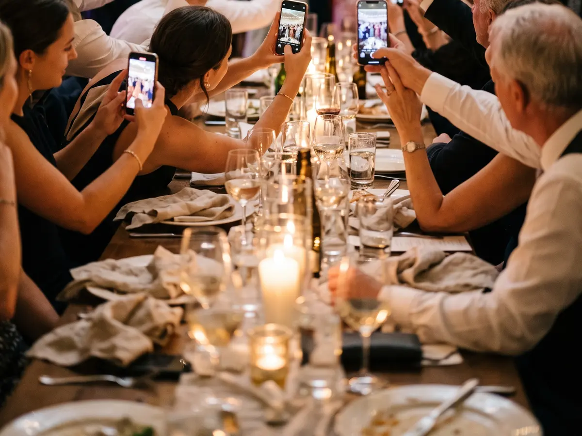 Invitados en un banquete de boda haciendo fotos con el móvil al mismo tiempo